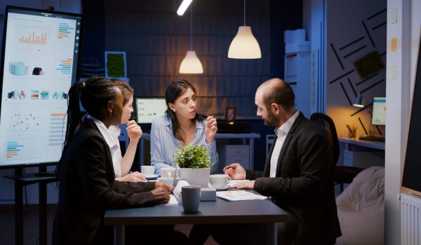 Executive manager woman explaining management statistics working at company strategy overtime in office meeting room. Diverse multi-ethnic businesspeople teamwork brainstorming ideas in evening