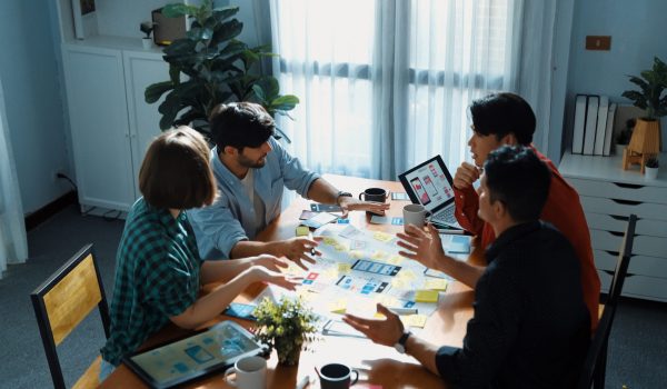 Top view of business team brainstorming idea by using mind map while clapping hand together. People designing Ux Ui design for mobile phone while making stack of hands and clapping hand. Convocation.